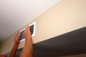 a man holding his hands up to an air vent to see how strong the airflow is
