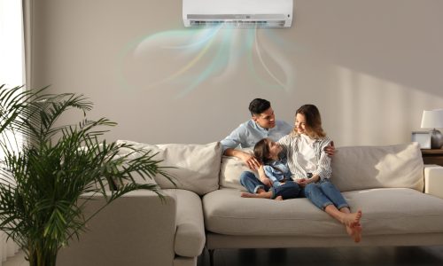 Happy family resting under air conditioner on beige wall at home Happy family resting under air conditioner on beige wall at home